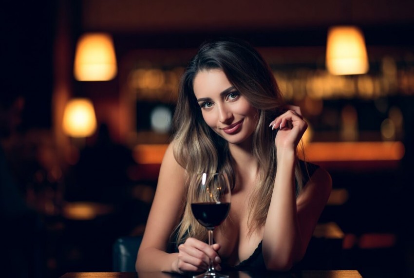 Smilende kvinde nyder et glas r&oslash;dvin p&aring; en bar &ndash; f&aring; de bedste dating profil tips dk til fr&aelig;k dating og en sikker f&oslash;rste date.