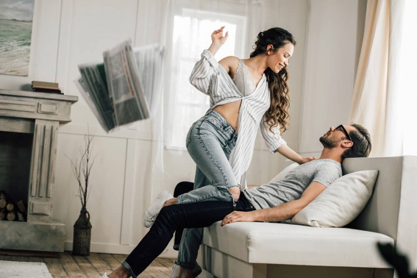 Lykkeligt par leger i sofaen med flyvende aviser &ndash; illustration af sp&aelig;ndingen ved gift s&oslash;ger gift og et diskret sidespring uden drama.