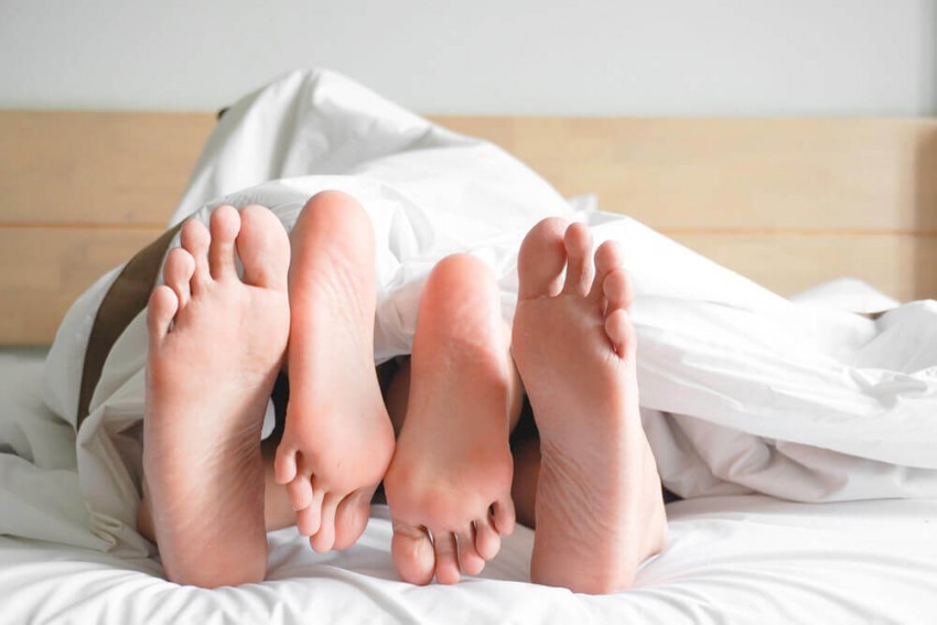 Lidenskabeligt par i sengen, hvor manden kysser kvindens hals under en hed adult dating-session.