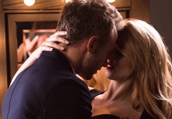 Dein heißer Sextreff.jpg«: Mand i jakkesæt, der er ved at kysse en kvinde med blondt hår og rød læbestift i en sensuel, intim stilling, der antyder et romantisk eller seksuelt møde.