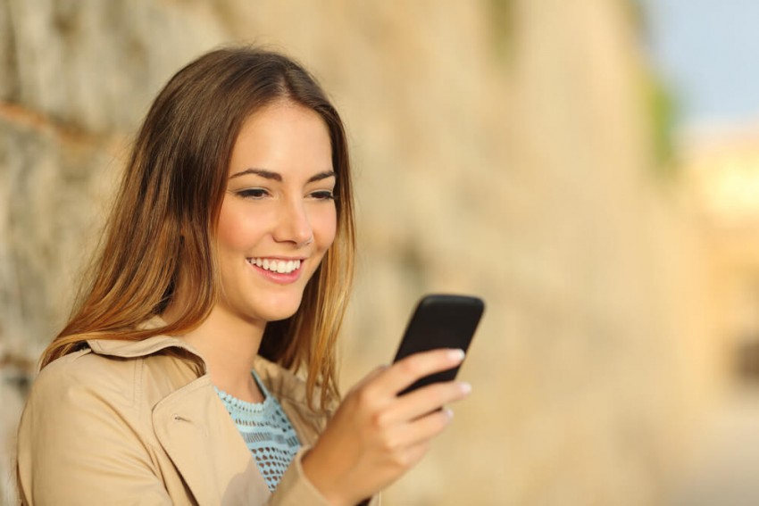 Kvinde i sort blonderundertøj tager et selfie i sengen, hvilket symboliserer videotelefonsex og intim chat.